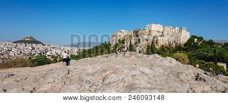 Panorama Of Tourists Gazing At The Acropolis Of Athens, Greece From A Rocky Hill Across The Acropoli
