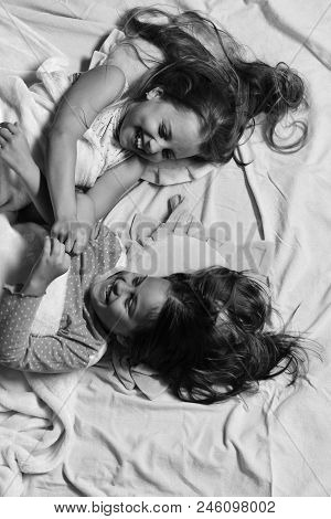 Schoolgirls In Pajamas Wallow On Colorful Pillows, Top View. Kids With Happy Faces Have Fun Lying In