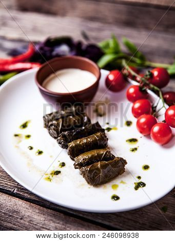 Cabbage Rolls In Grape Leaves With Sauce And Tomatoes. Food A