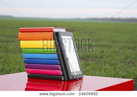 Pile de livres colorés et de lecteur de livre électronique à l'extérieur