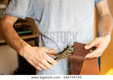 Making Holes With Puncher In Leather Workshop. Male Hands With Eyelet Puncher Working With Piece Of 