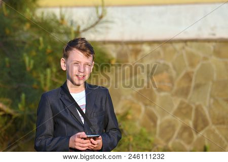 A Boy With A Smartphone Reads A Message In The Smartphone And Looks At The Camera.