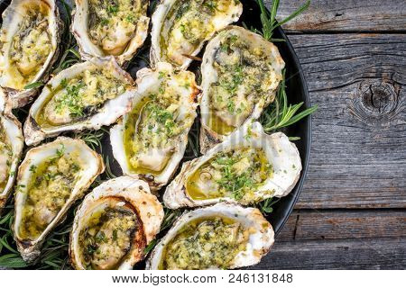 Barbecue overbaked fresh opened oyster with garlic and herbs offered as top view on a tray with copy space right 