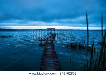 Blue Dock With Blue Sky Along The Lake Shore Before Sunset In Blue, El Remate, Peten, Guatemala