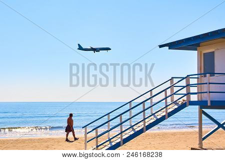 Plane Landing Over A Beach With Lifeguard Station Booth, Vacation Time
