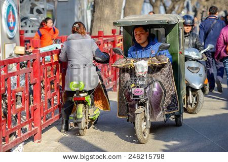 Beijing, China - March 10, 2016: People Are Driving Through The Streets With Bicycles, Scooters And 