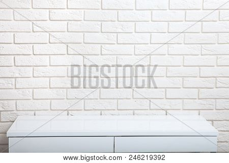 White Table Near The White Wall. Empty Workplace In The Room. White Background Mock Up.