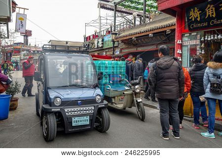 Beijing, China - March 12, 2016: People Are Driving Through The Streets With Bicycles, Scooters And 