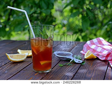 Cool Drink, Cold Black Tea With Lemon, Mint And Ice In Tall Glasses On A Wooden Background. Summer C