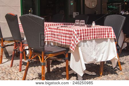 Table Set With Red And White Checkered Tablecloth Outside A  Characteristic Trattoria Of Milan