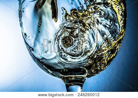 White Wine Splash On Grey Background, Stream Of White Wine Pouring Into A Glass. Bright View Photo.