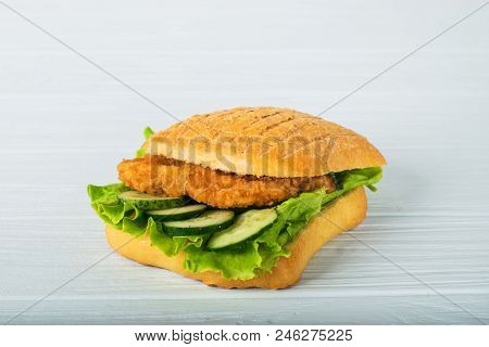 Pressed And Toasted Double Panini With Ham And Cheese Served On Sandwich Paper On A Wooden Table