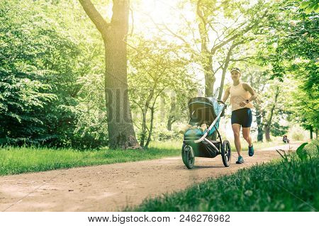 Running Woman With Baby Stroller Enjoying Summer Day In Park. Jogging Or Power Walking Supermom, Act