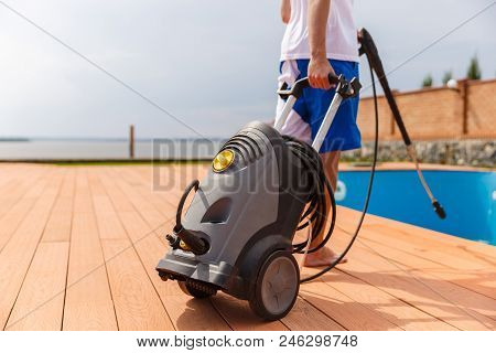 A Man Is Cleaning A Cool Swimming Pool With The Hepl Of A Vacuum Cleaner.