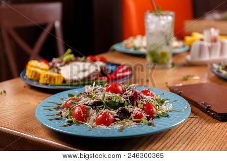 A Plate With Caesar Salad And Other Italian Dishes Are Layed Out On The Table, Covered With The Beig