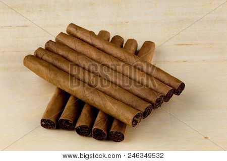 Small Cigars Piled On A Wooden Table Top