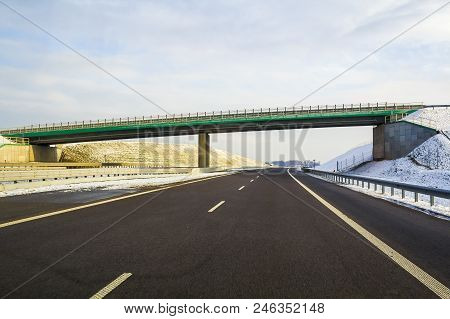 Modern Wide Smooth Empty Asphalt Highway Stretching To Horizon Under High Bridge Turning Right Past 