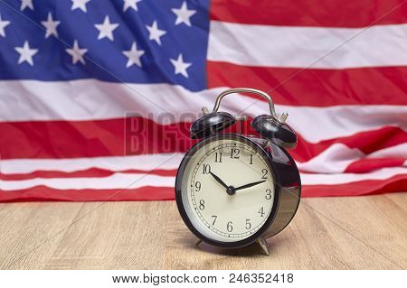 National flag of America and black alarm clock on old wooden background
