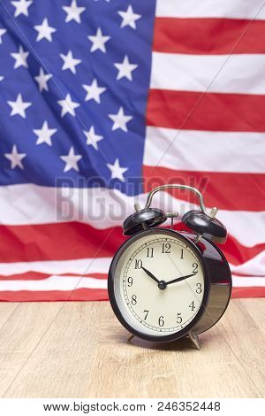 National flag of America and black alarm clock on old wooden background