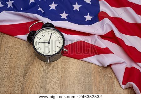 National flag of America and black alarm clock on old wooden background