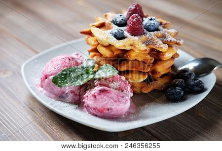 Plate of belgian waffles with ice cream and fresh berries - raspberries and blueberries
