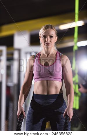 young fit athlete woman working out in functional training gym doing  battle ropes exercise as part of cross fitness training