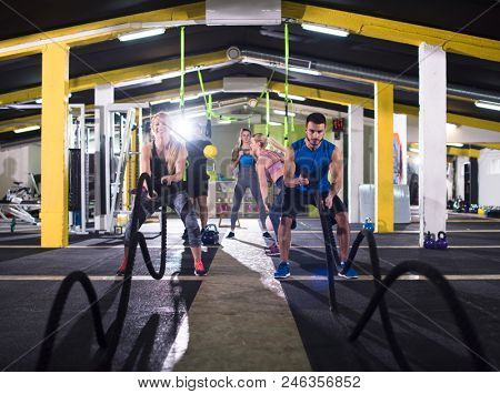 young fit sports couple working out in functional training gym doing  battle ropes cross fitness exercise