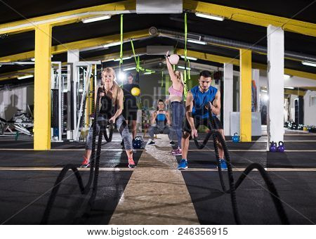 young fit sports couple working out in functional training gym doing  battle ropes cross fitness exercise