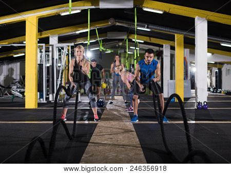young fit sports couple working out in functional training gym doing  battle ropes cross fitness exercise