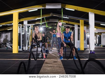 young fit sports couple working out in functional training gym doing  battle ropes cross fitness exercise