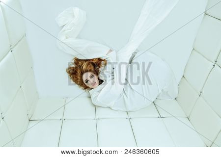 Portrait of a crazy girl dressed in a straitjacket in an isolated room in a madhouse.