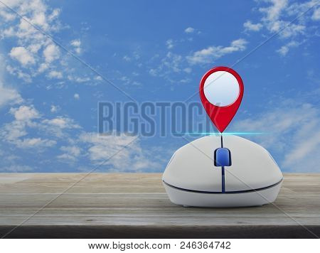 Map Pin Location Button With Wireless Computer Mouse On Wooden Table Over Blue Sky With White Clouds