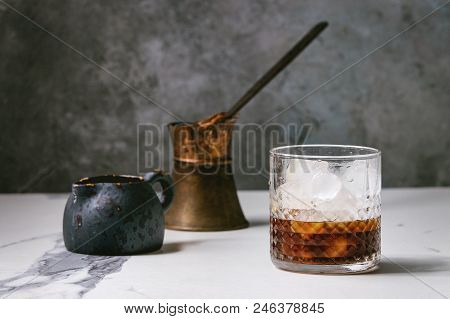 Iced Coffee Cocktail Or Frappe With Ice Cubes In Glass With Vintage Jezva And Milk Jug On White Marb