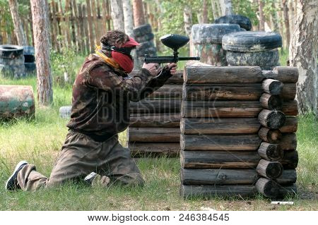 A Guy Or Girl In Camouflage Clothes Peeks Out From Behind A Wooden Shelter With A Weapon In Hand. La