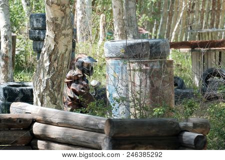 Extreme Team Sport.a Guy During A Game Of Paintball On The Landfill. Camouflage Suit, Protective Mas