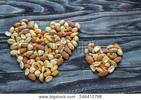 Mix Nuts In A Pottery On A Wooden Background In The Form Of A Heart.