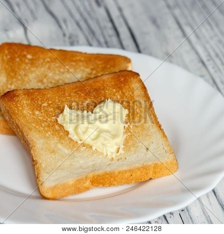 Still Life With Bread And Butter In A White Plate On A Wooden Background