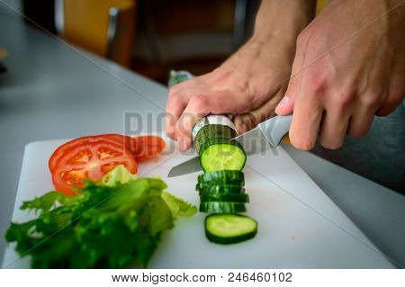 Left Handed Man Cutting Cucumber, Tomato And Salad.