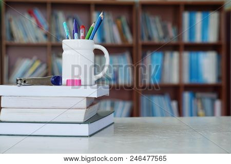 Pencil, books and notebooks on the library desk for reading.