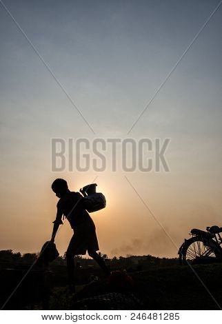 Mrauk U Myanmar On March 20, 2016: Silhouette Of Boy Who Was Fetching Water In Sunset Time