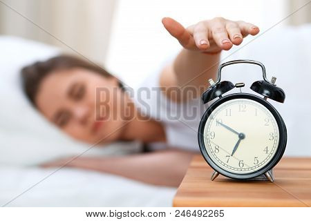 Sleepy Young Woman Stretching Hand To Ringing Alarm Willing Turn It Off. Early Wake Up, Not Getting 