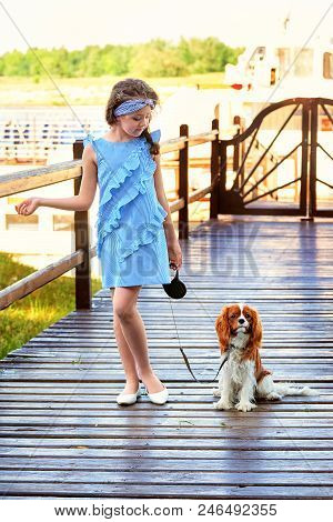 Elegant Child Near Puppy Breed Cocker Spaniel,charles King.beautiful Young Girl Stands Bridge Pier. 