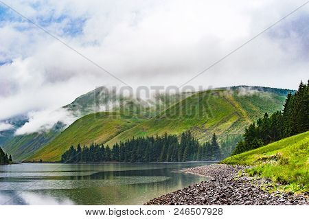 View Of A Beautlful Lake Talla In Scottish Borders With Green Hills Covered By Thick Rainy Clouds.