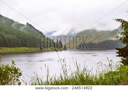 View Of A Beautlful Lake Talla In Scottish Borders With Green Hills Covered By Thick Rainy Clouds.