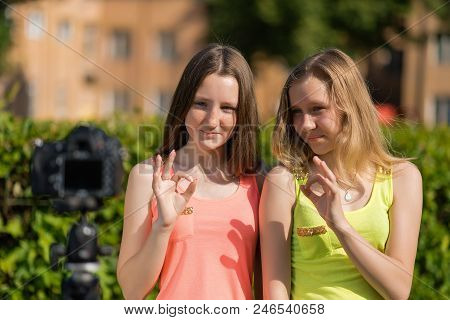 Two Girls In The Summer In The Park. Summer In Nature. Young Girlfriends Bloggers Showing Gestures O