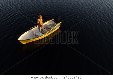 Lulea, Sweden - June 16, 2018: A Man And His Dog Standing In A Rowing Boat Fishing At Sunset.