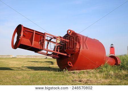 A Large Red Navigation Buoy With The Charlevoix South Pier Light Station Can Be Seen In The Backgrou