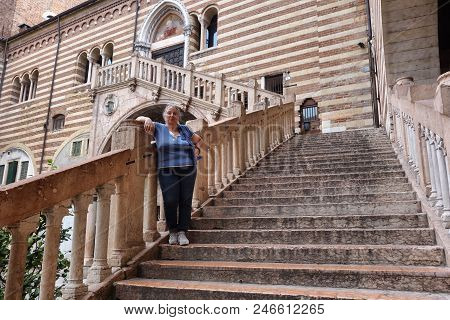 Verona, Italy , Female Tourist Posing On The Scala Della Ragione Stairs At The Palazzo Della Ragione