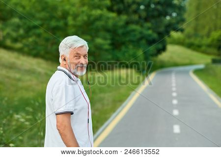 Portrait Of Smiling Old Man Standing On City's Racetrack Looking At Camera.