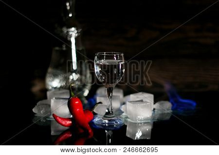 A Shot Of Vodka, An Alcoholic Beverage, Next To Ice, Fire, Ice, Red Chili Pepper. The Concept Of Alc